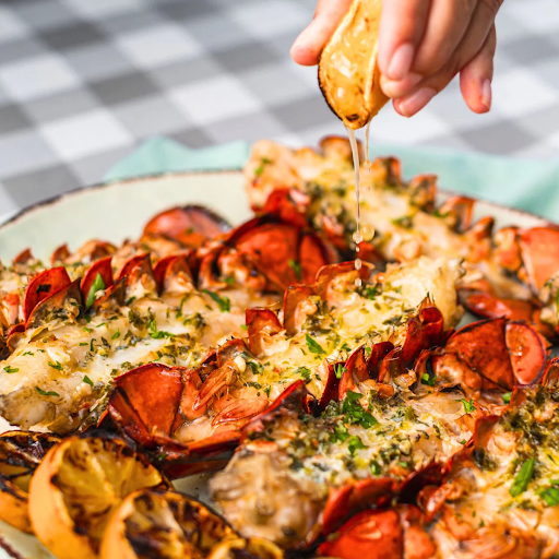 Grilled Maine lobster tails topped with melted herb butter and lemon juice, perfect for an elevated Easter brunch.