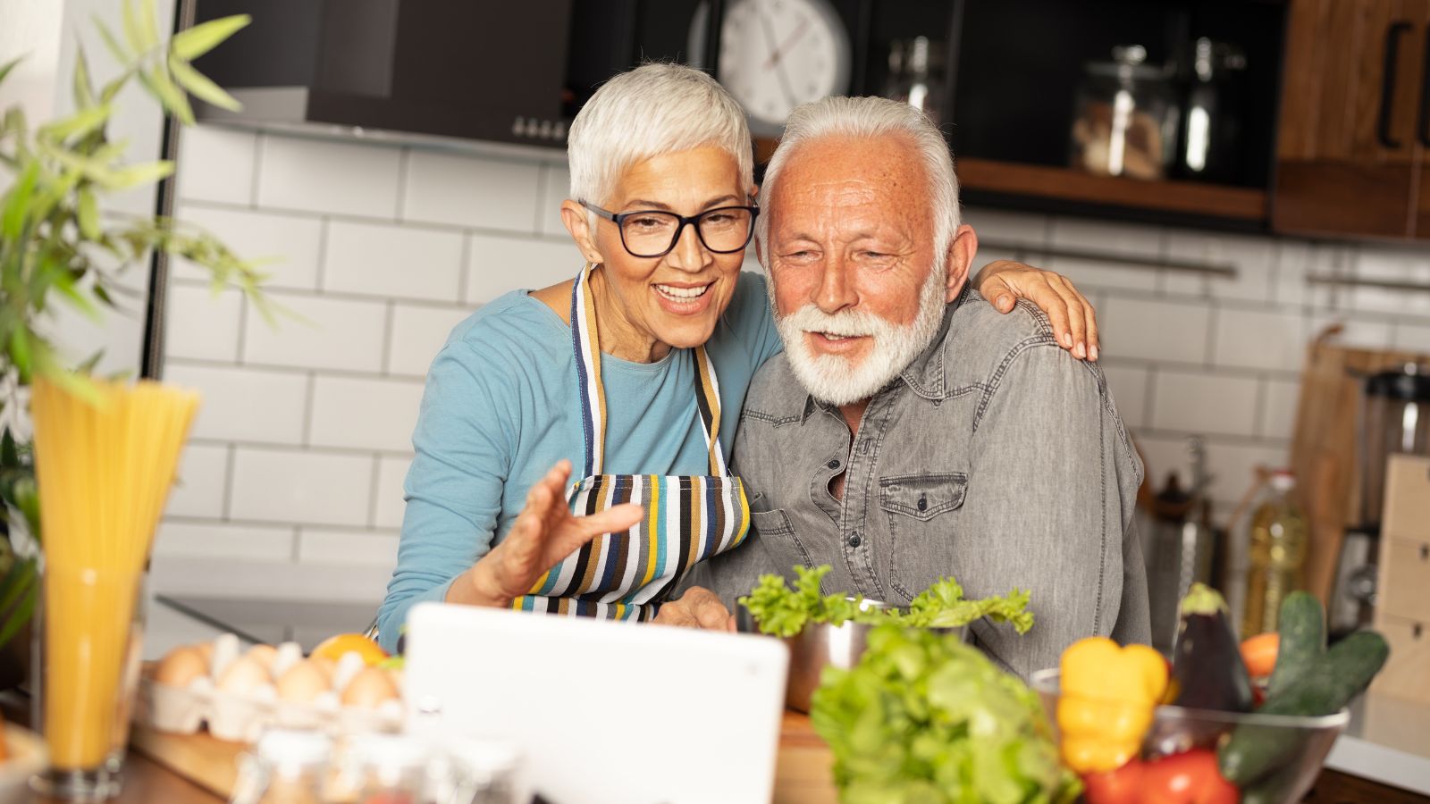An older couple joyfully preparing a meal together in their kitchen, sharing a moment of connection, perfect for creating lasting memories.