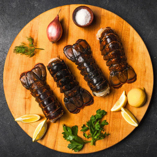 Cooked lobster tails are kept on a wooden platter, served with lemon and mint to their highness.
