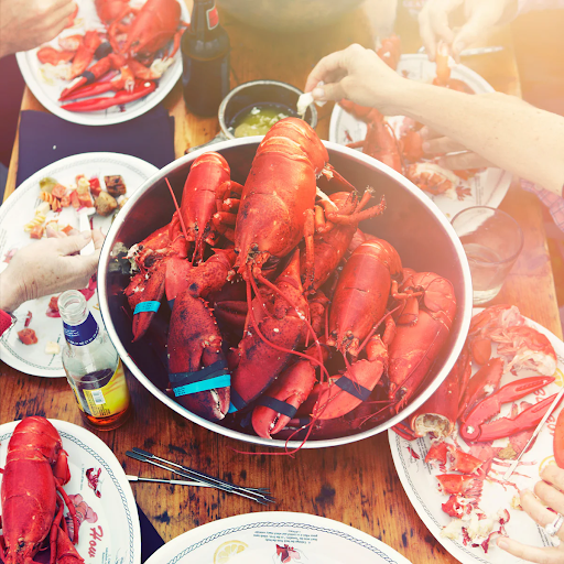 Steamed Maine Lobster on a rustic coastal-themed table with nautical decor and red accents.