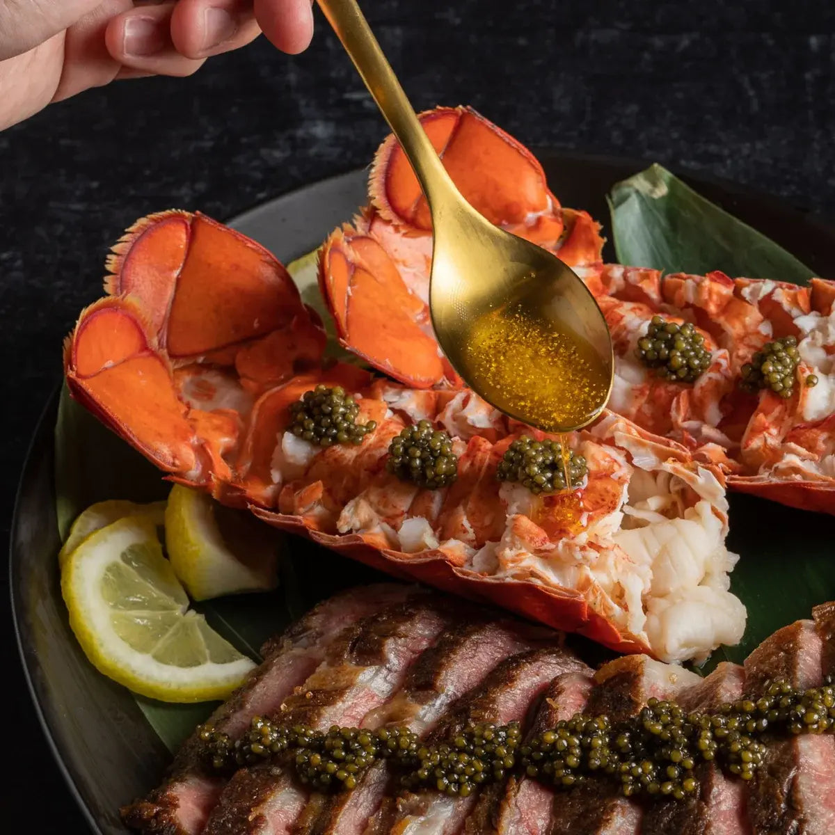 Butter-poached Maine lobster tails with caviar, served with lemon and seared steak.