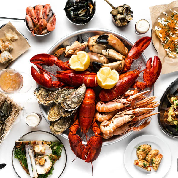 Gourmet seafood platter with jumbo Maine lobster, oysters, shrimp, and lemon slices.